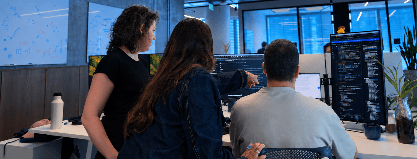 Team members discussing code in front of computer monitors
